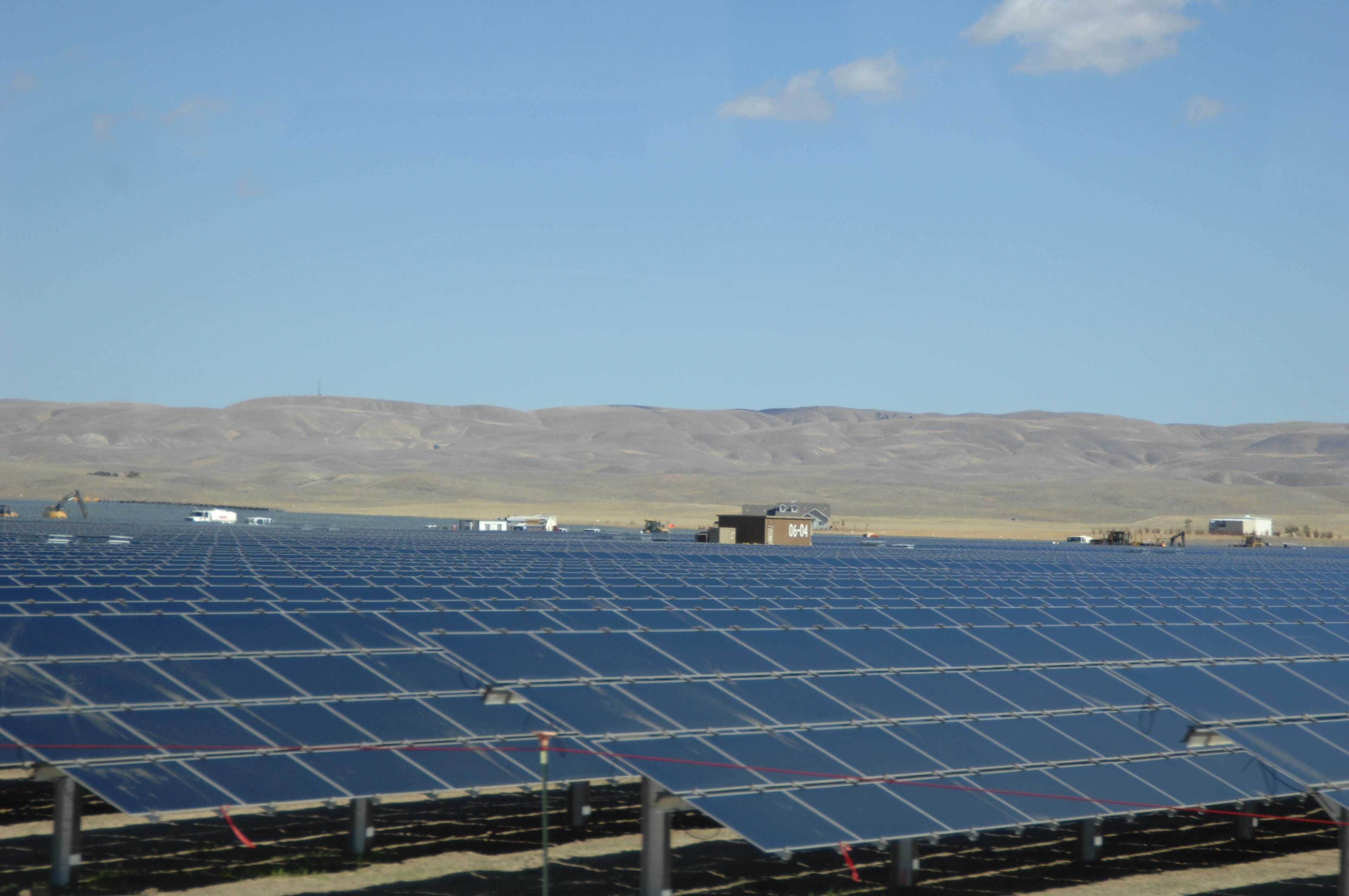 Campo de módulos fotovoltaicos se estendendo até as colinas